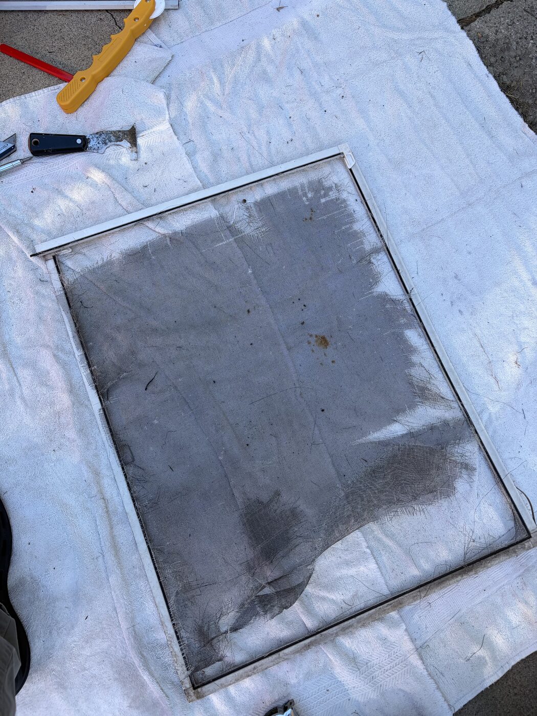 Damaged window screen mesh before rescreening